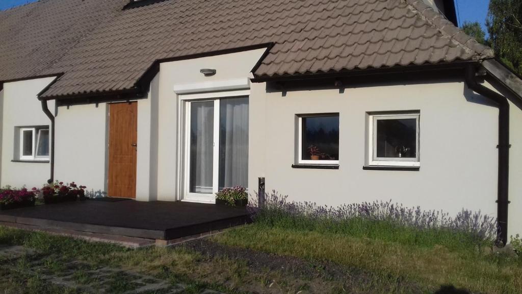 a white house with a porch and a door at Agroturystyka za lasem in Kiekrz
