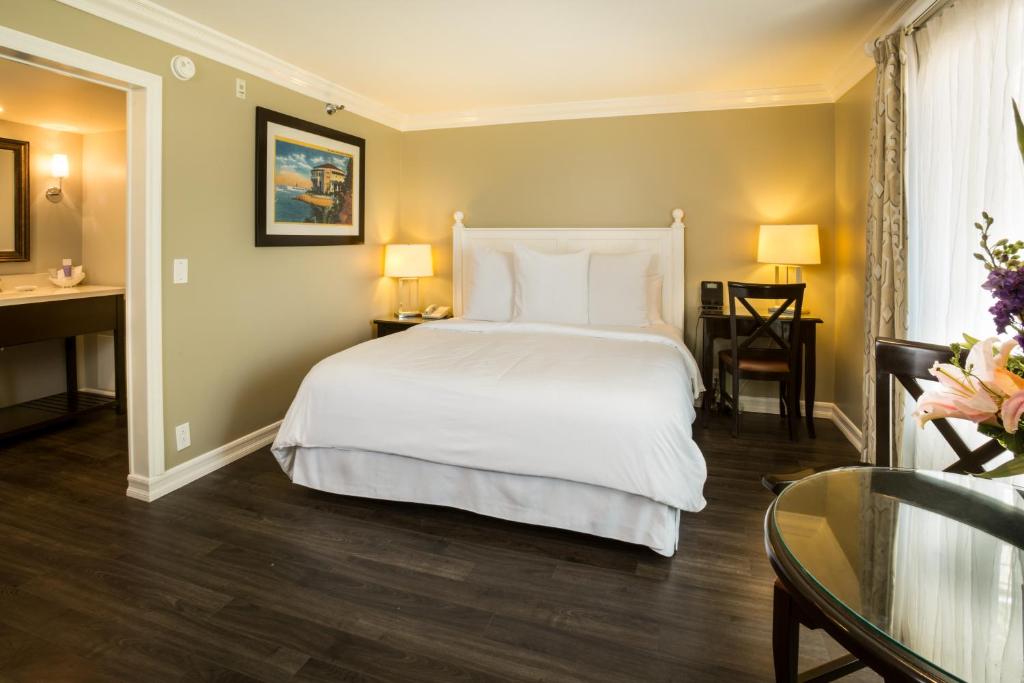 um quarto com uma cama branca e uma mesa em Hotel Metropole em Avalon