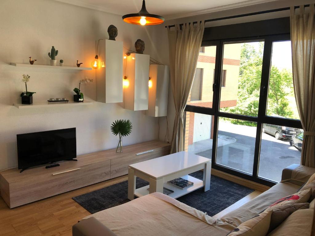 sala de estar con sofá, TV y mesa en Apartamento Ezcaray con Piscina, en Zorraquín