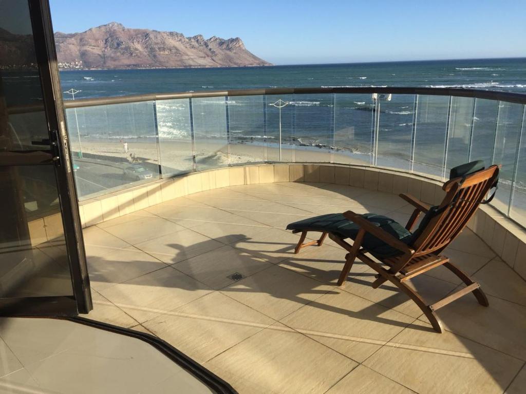 einen Schaukelstuhl auf einem Balkon mit Meerblick in der Unterkunft Full OCEAN VIEW Seaside Luxury Spacious Suite XXXL in Strand