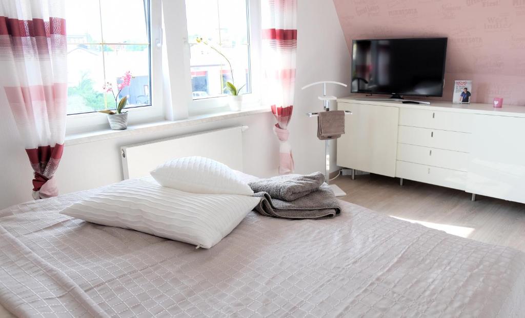 1 dormitorio con 1 cama blanca, TV y ventanas en Heimathafen Weimar, en Weimar