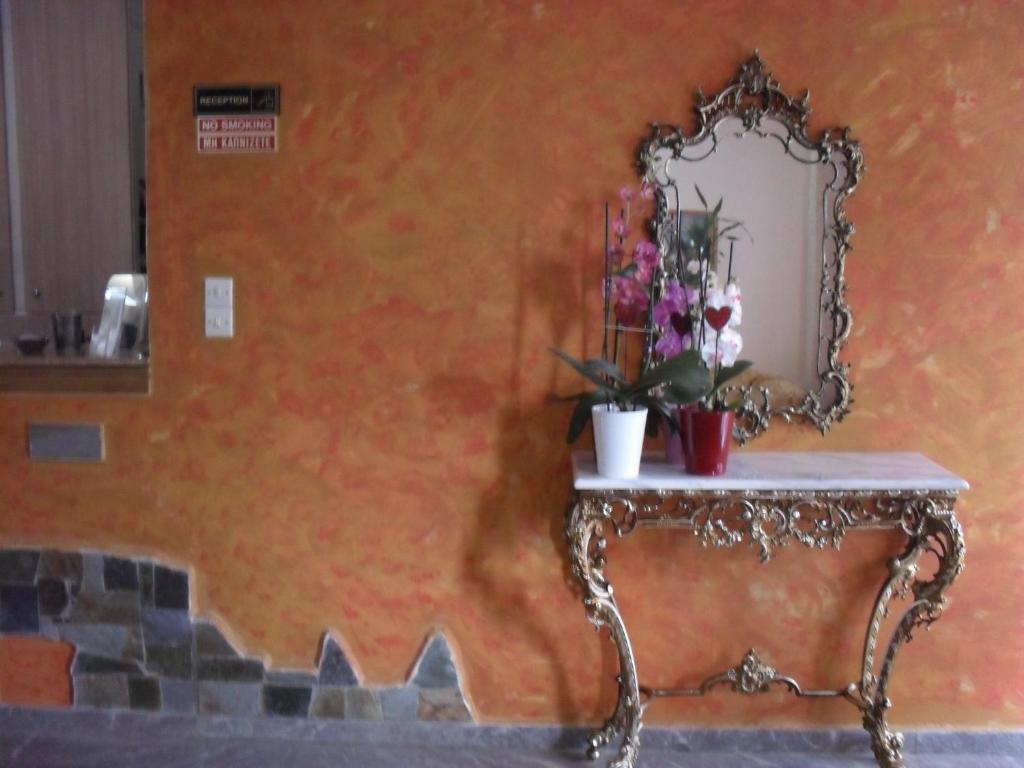 an orange wall with a mirror and a table with flowers at La Santre Villa in Amoudara Herakliou