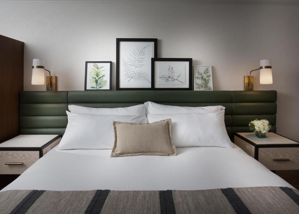 a bedroom with a white bed with a green headboard at The Ingleside Hotel in Waukesha