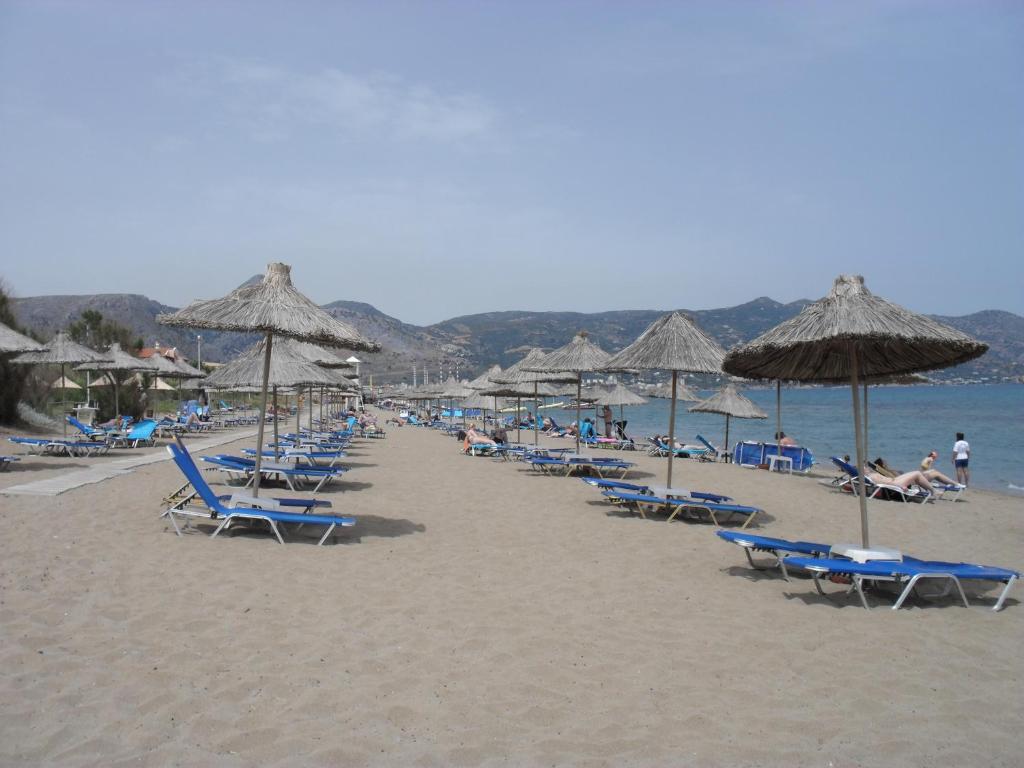 a group of chairs and umbrellas on a beach at La Santre Villa in Amoudara Herakliou