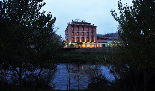 a large building with lights on in front of a river at Hotel Cavour in Rieti