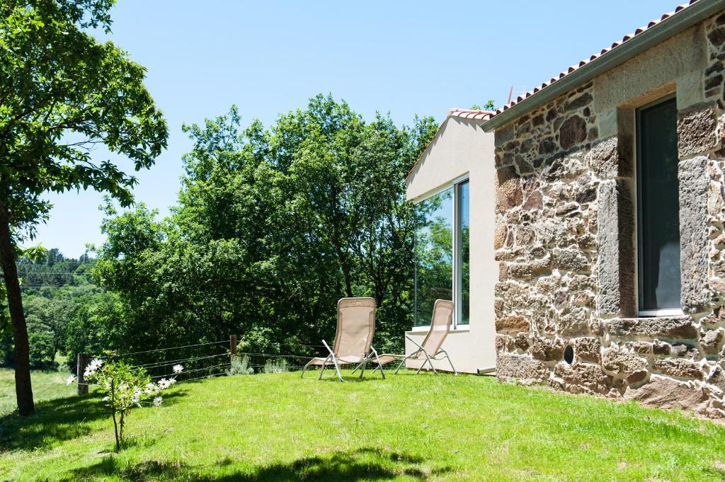 una casa de piedra con 2 sillas en el patio en Casa das Landras, en Chantada