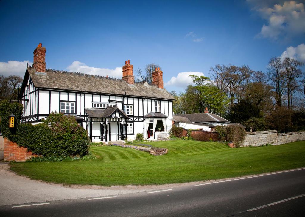 una vieja casa en blanco y negro con un patio verde en Donington Park Farmhouse Hotel en Castle Donington