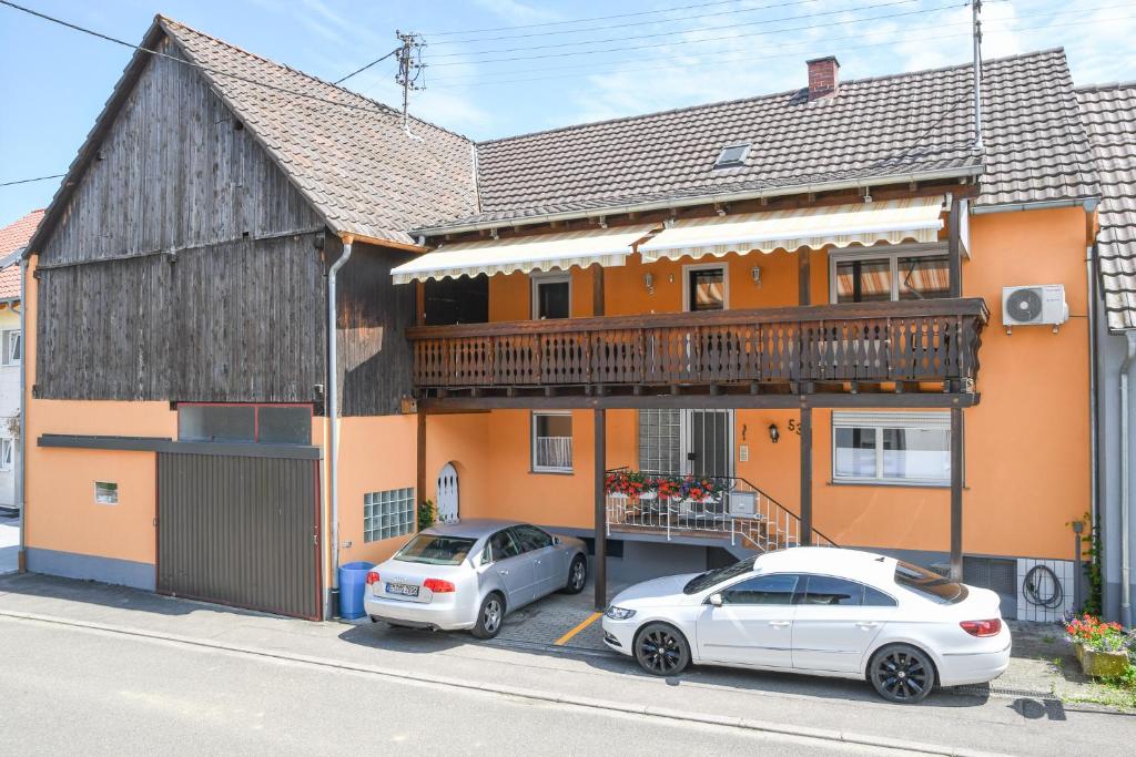 zwei Autos, die vor einem Haus mit Balkon geparkt sind in der Unterkunft Ferienwohnungen zur Elz in Kappel-Grafenhausen