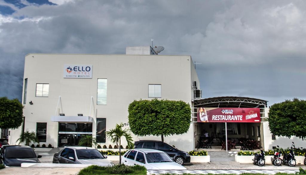 un edificio blanco con coches estacionados en un estacionamiento en Ello Hotel, en Iguatu