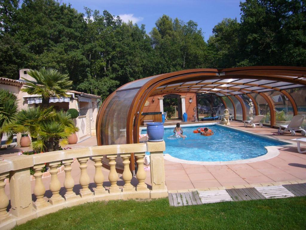 - une piscine avec une structure en bois avec des personnes dans l'établissement Chambre et table d'hôtes Villa Pomponette, à Nans-les-Pins