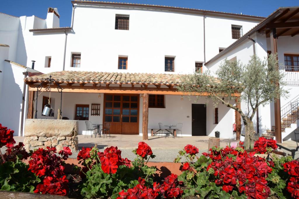 uma casa com flores vermelhas em frente em Casa Rural Aromas de la Manchuela em Alborea