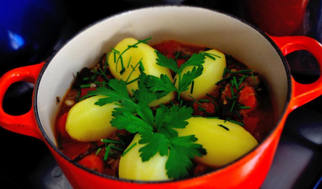 a red pot filled with vegetables with parsley on top at La Maison de l'Omignon in Vermand
