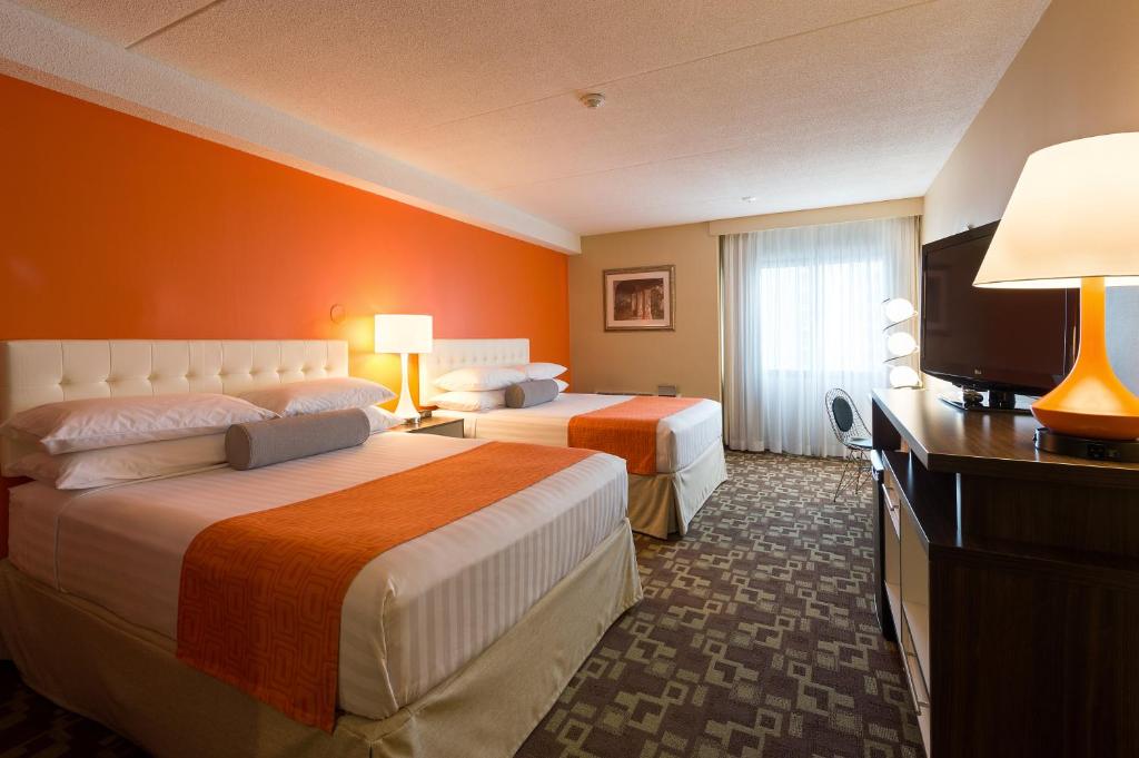 a hotel room with two beds and a flat screen tv at Howard Johnson Plaza by Wyndham by the Falls Niagara Falls in Niagara Falls