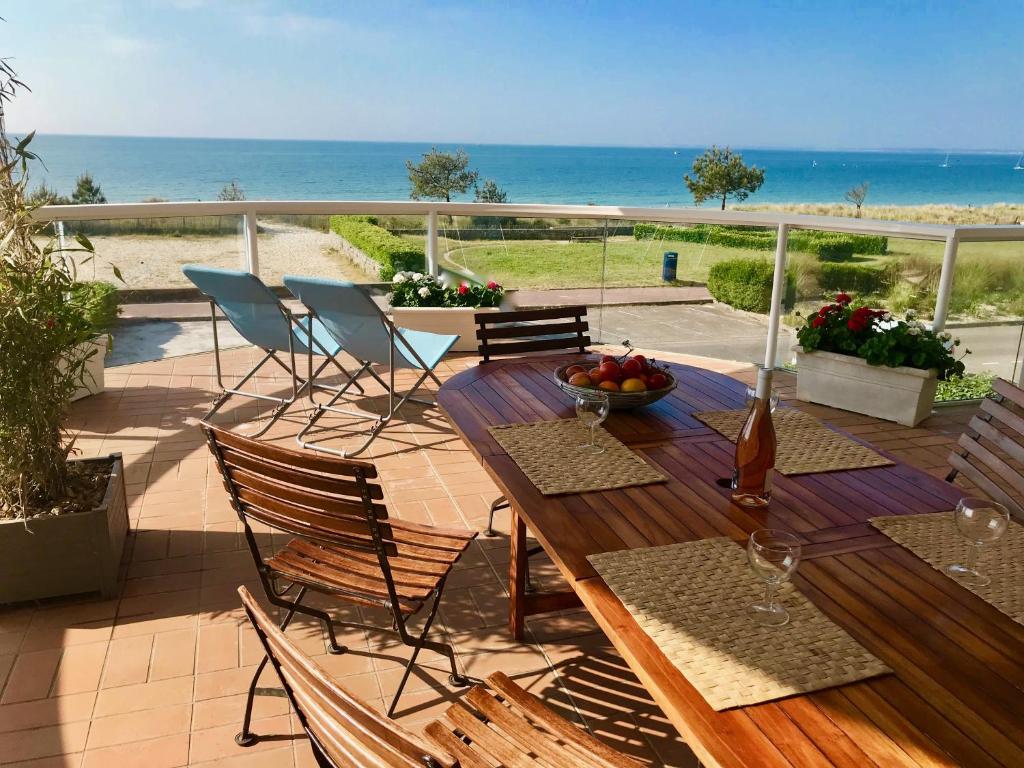 Front de mer - Victoria - Appartement 120m2 في كارناك: طاولة وكراسي خشبية على فناء مع المحيط
