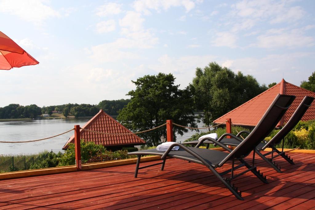 2 Stühle auf einer Terrasse mit Blick auf das Wasser in der Unterkunft Port Jeziorak in Iława