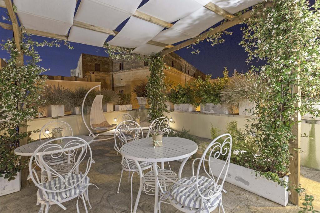 un patio con mesas, sillas y hiedra en La Loggia dei Raynò en Lecce