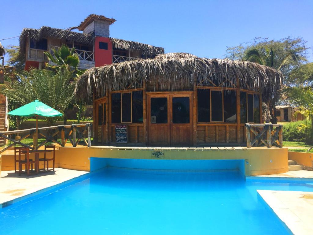 un complejo con piscina y un edificio con techo de paja en El Mirador de Vichayito, en Vichayito