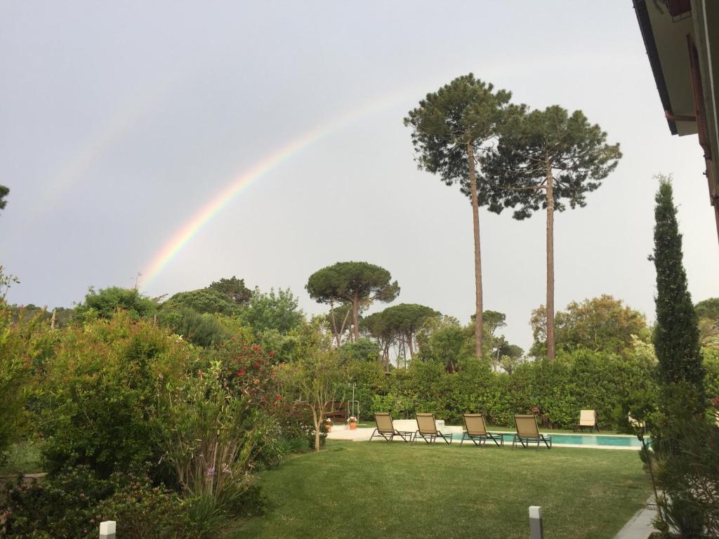 a rainbow over a yard with chairs and a pool at Arli Hotel Hideaway Punta Ala - Adults Only in Punta Ala