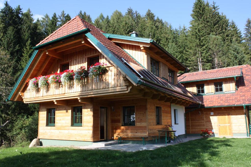 una casa de madera con flores en el balcón en Stillbacherhütte, en Mariahof
