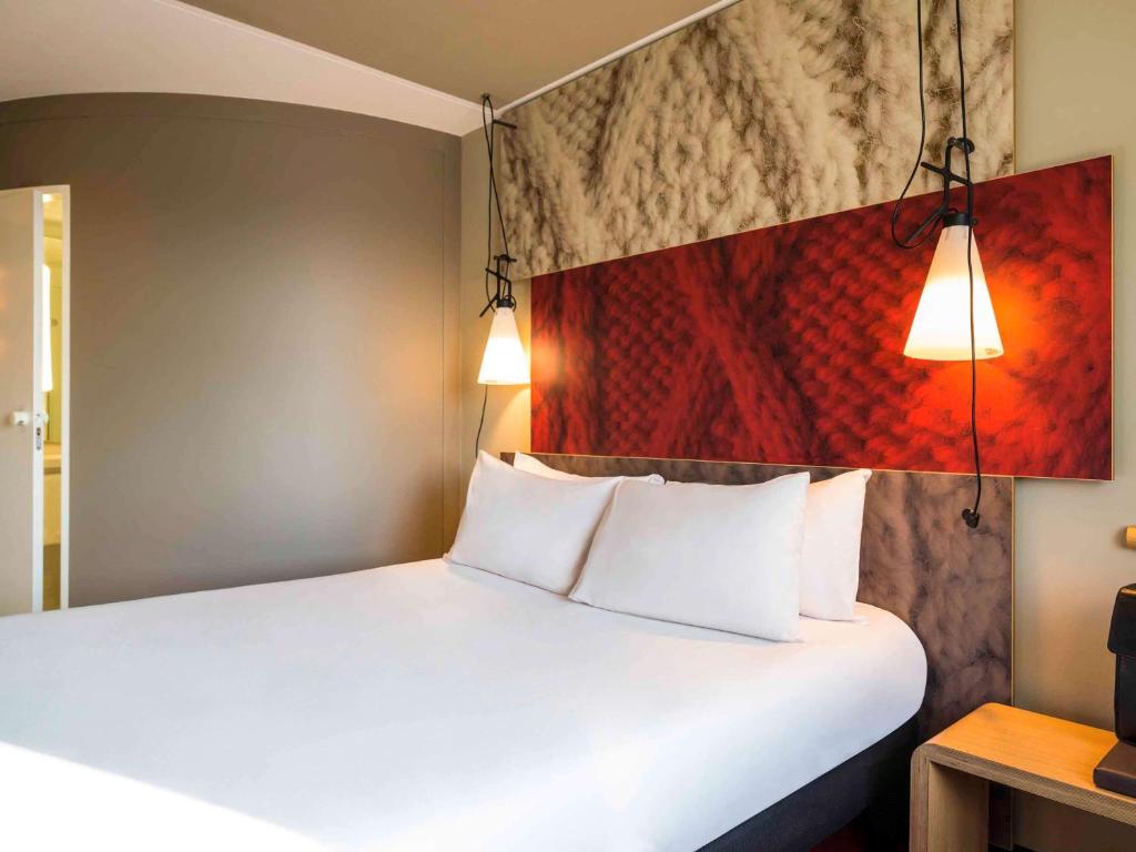 a bedroom with a white bed with two pillows at Ibis Schiphol Amsterdam Airport in Badhoevedorp