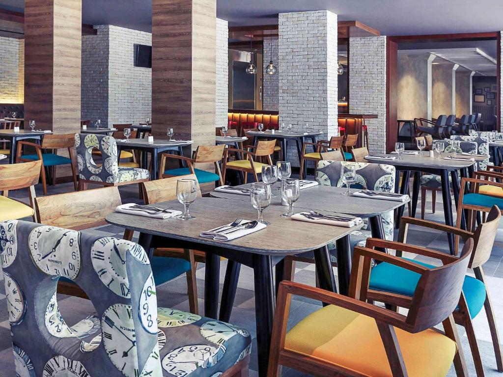 a restaurant with tables and chairs with wine glasses at Mercure Jakarta Sabang in Jakarta