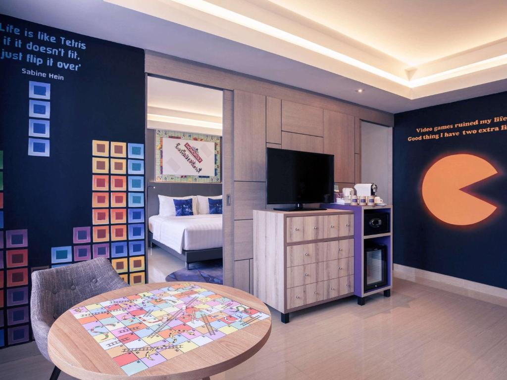 a room with a bed and a table and a tv at Mercure Jakarta Sabang in Jakarta