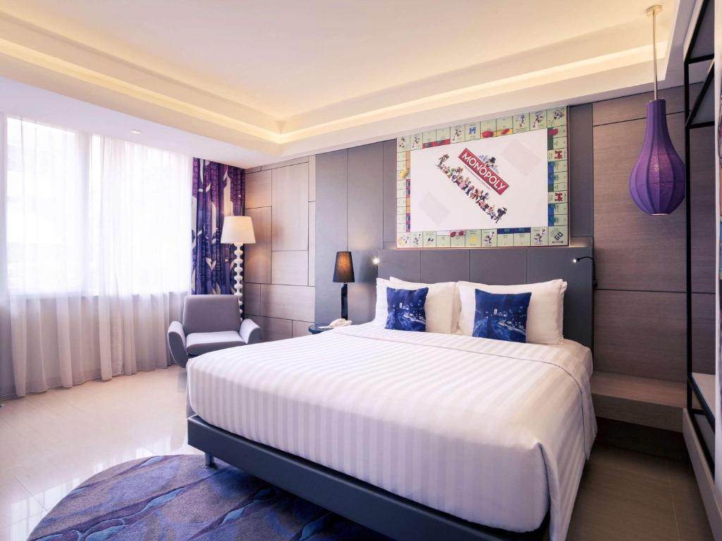 a hotel room with a large bed and a chair at Mercure Jakarta Sabang in Jakarta