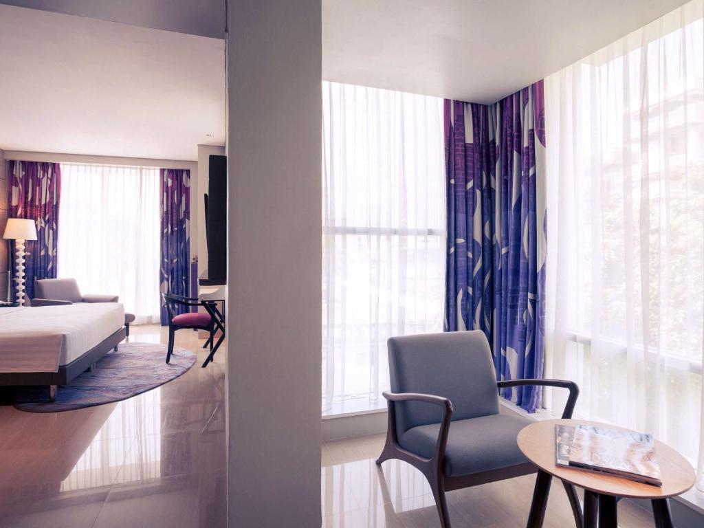 a living room with a bed and a room with a bed and windows at Mercure Jakarta Sabang in Jakarta