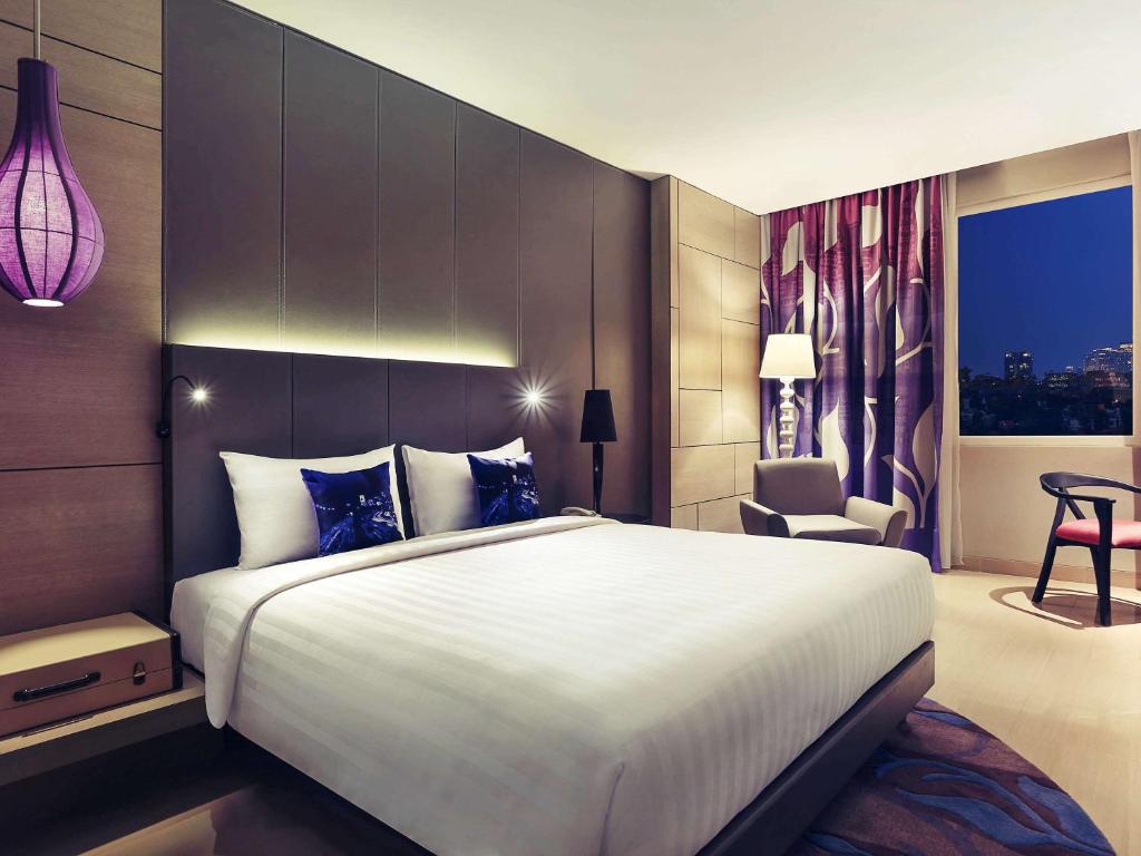 a hotel room with a large bed and a chair at Mercure Jakarta Sabang in Jakarta