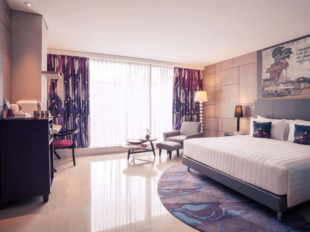 a hotel room with a bed and a living room at Mercure Jakarta Sabang in Jakarta