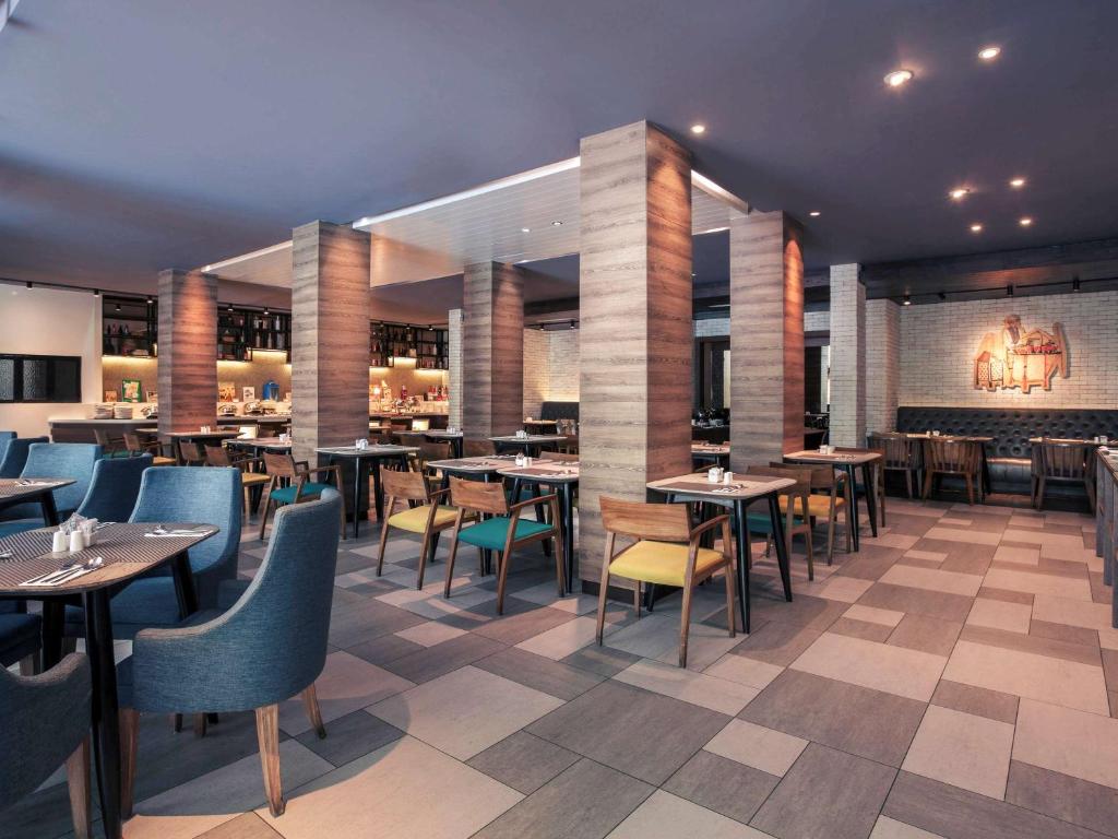 a restaurant with tables and chairs and a bar at Mercure Jakarta Sabang in Jakarta