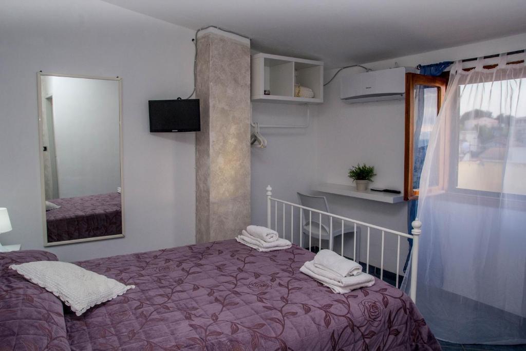 een slaapkamer met een bed, een spiegel en een raam bij B&B Villa San Nicola in San Nicola Arcella