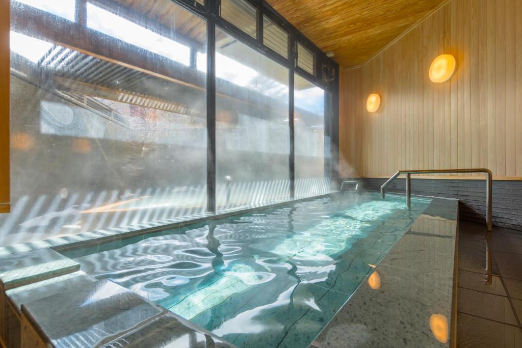 a swimming pool in a building with a large window at Hotel Hanaan in Nikko
