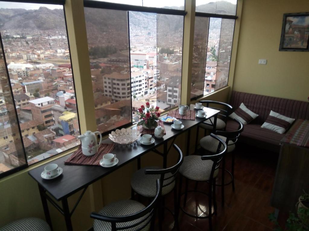 a restaurant with a table and chairs in a room with large windows at Casa Hospedaje Killari in Cusco