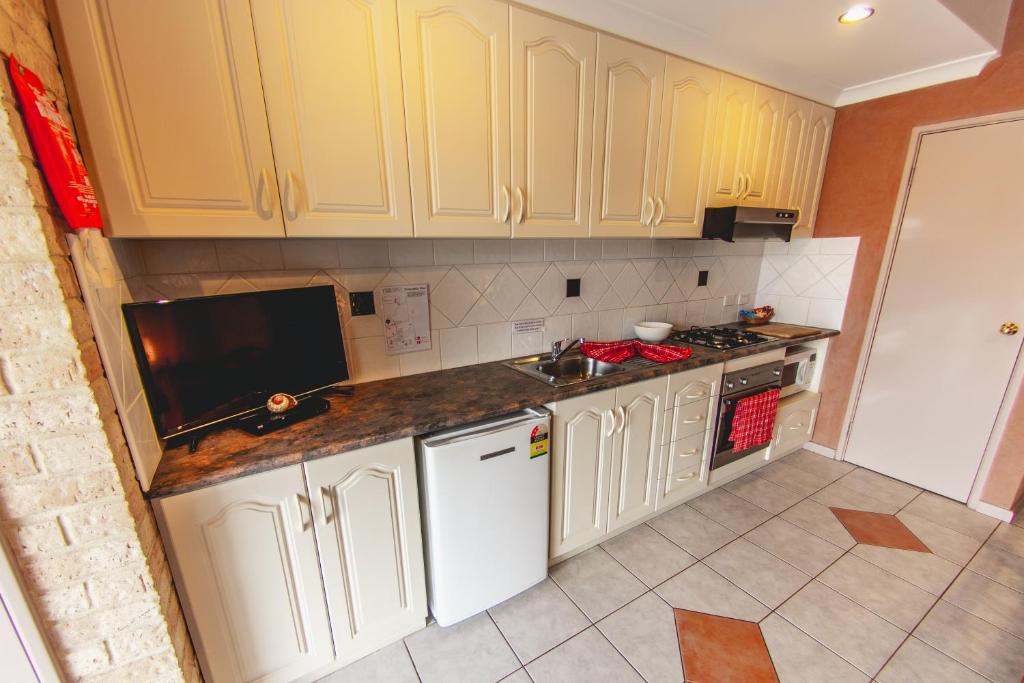 a kitchen with white cabinets and a white refrigerator at Esperance Foreshore Apartments in Esperance