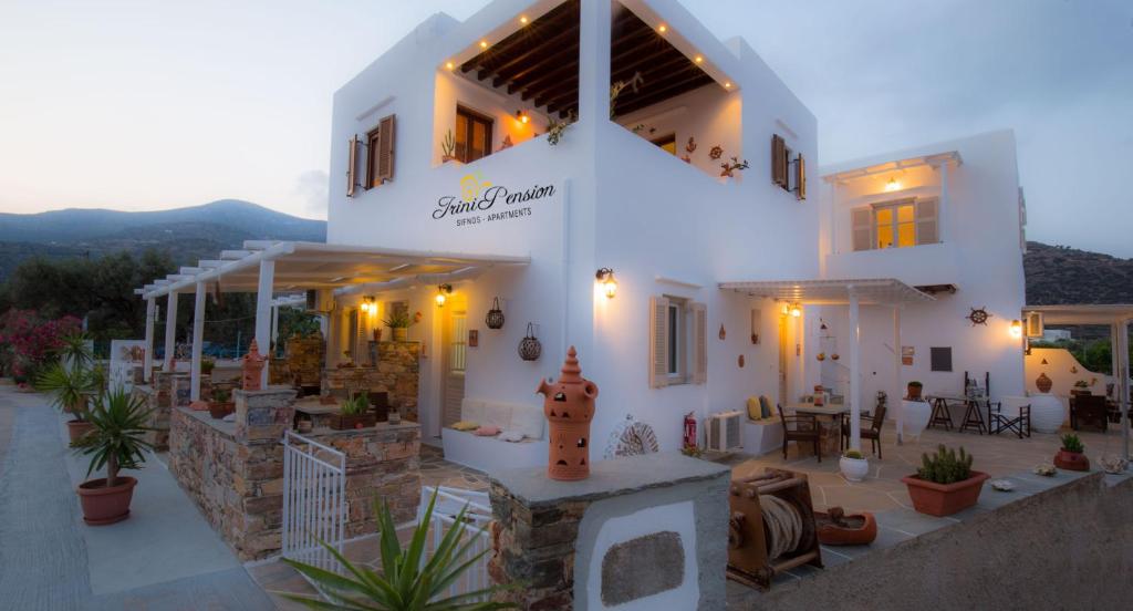 een groot wit huis met een zonsondergang op de achtergrond bij Irini pension in Platis Yialos Sifnos