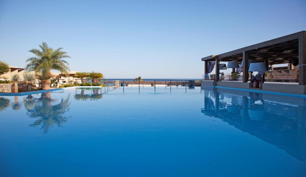 a large pool of blue water next to a resort at Aquagrand Exclusive Deluxe Resort Lindos - Adults only in Líndos