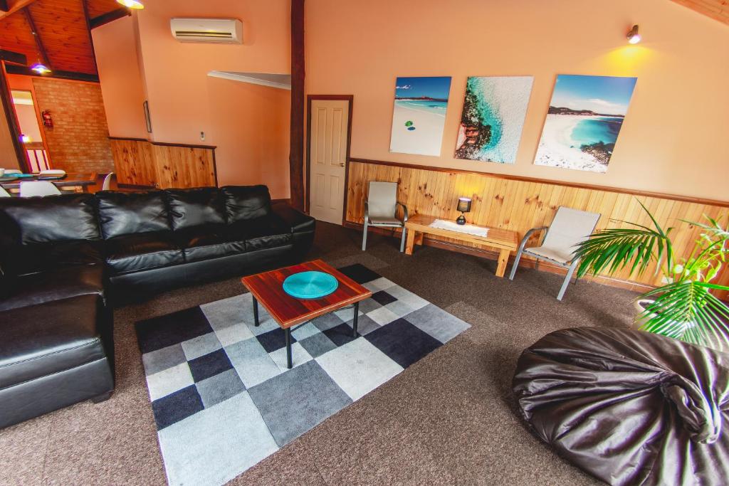 a living room with a black leather couch and a table at Esperance Foreshore Apartments in Esperance
