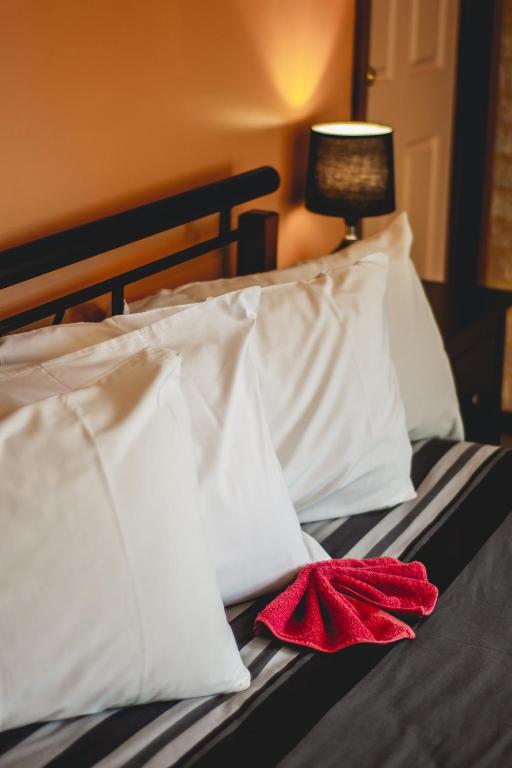 a bed with white pillows and a red towel on it at Esperance Foreshore Apartments in Esperance