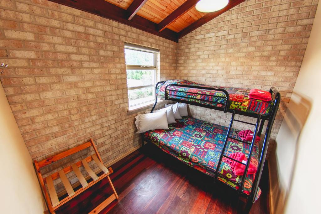 a room with two bunk beds in a brick wall at Esperance Foreshore Apartments in Esperance