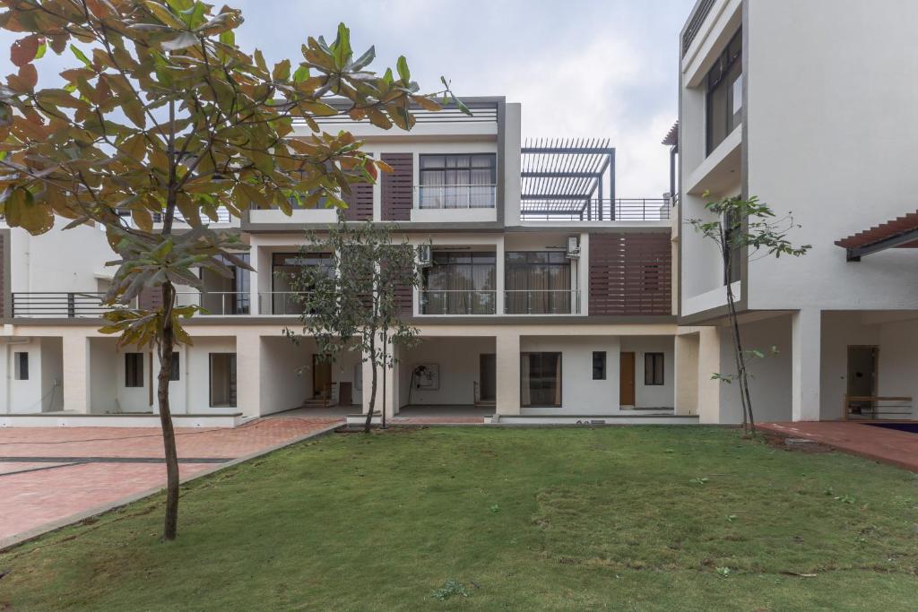 an apartment building with a yard in front of it at StayVista's Greenwoods Villa 9 - City-Center Villa with Private Pool, Terrace, Lift & Ping-Pong Table in Lonavala