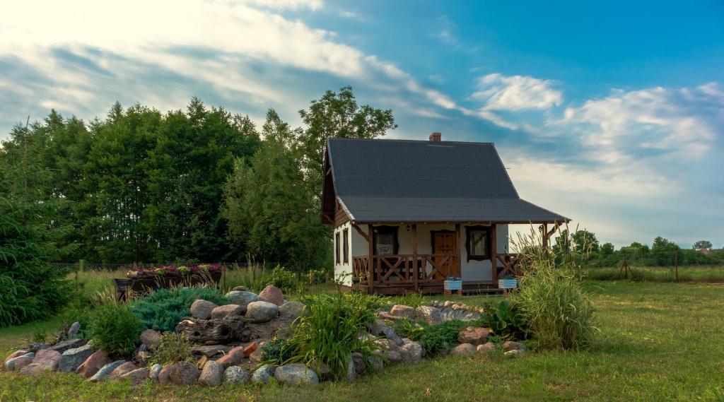a small house in a field with a rock garden at BIAŁY DOMEK in Ryn