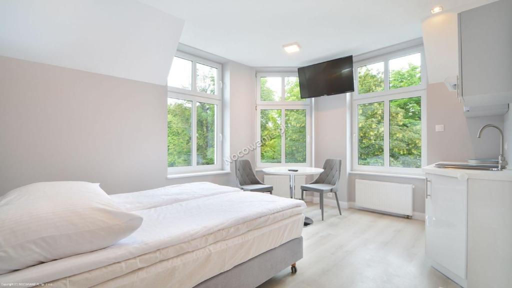 ソポトにあるHello Sopot by OneApartmentsの白いベッドルーム(ベッド1台、テーブル、椅子付)