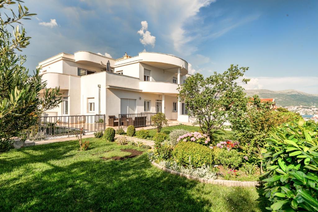 une maison blanche avec un jardin en face dans l'établissement Apartments Jokica, à Split