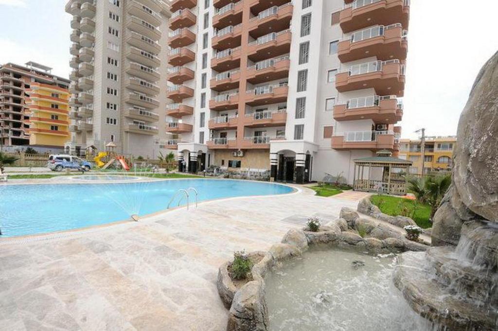 a swimming pool in front of some tall buildings at Yenisey Residence 2 in Mahmutlar