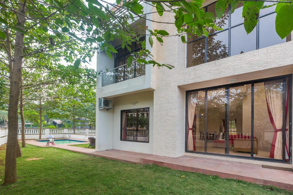 Un edificio con grandes ventanales y un patio. en StayVista's Greenwoods Villa 9 - City-Center Villa with Private Pool, Terrace, Lift & Ping-Pong Table, en Lonavala