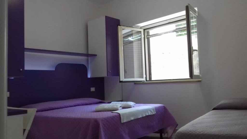 a purple room with two beds and a window at Il Corvino in Diamante