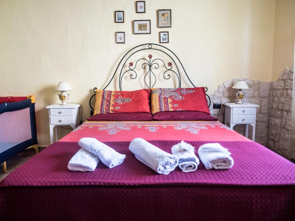 Una cama rosa con dos pares de zapatillas. en Villetta Rombi, en Calasetta