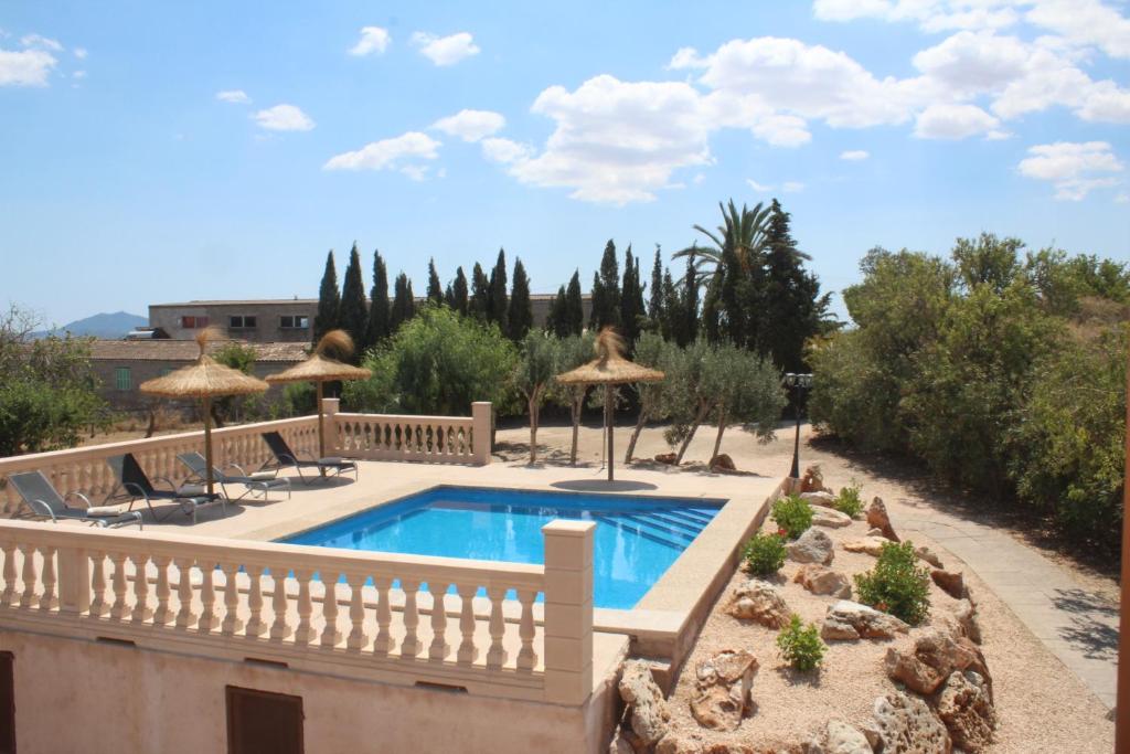 a swimming pool in a yard with umbrellas at Es Lladoner Villa in Porreres