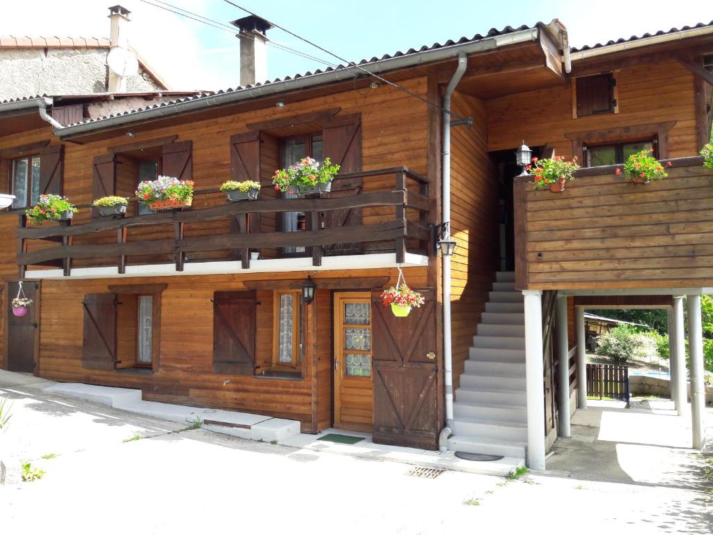 a wooden house with potted plants on the balconies at Au chalet d'Anna in Saint-Rambert-en-Bugey